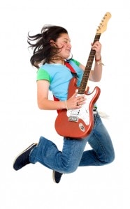 Teenage girl jumping with an electric guitar