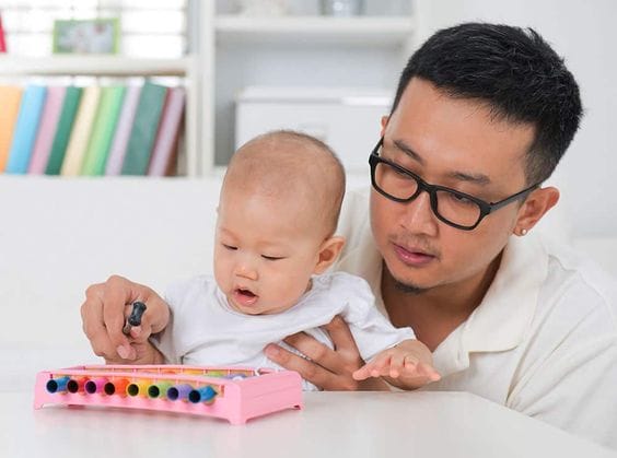 Dad helping his little one to hold and play the Xylophone
