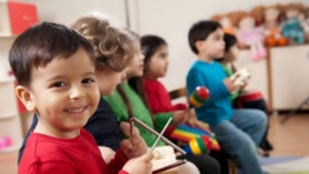 Several kids playing musical instruments. Toddler smiling as a foreground