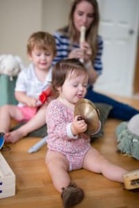 Cute baby girl wearing pink, enjoying at playing small Cymbal, closing her eyes
