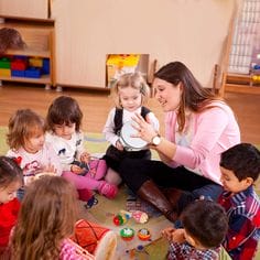 Toddlers playing musical instruments, singing and clapping, with their teacher.
