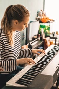 Teenager woman, white and black striped T-shirt, playing the piano.