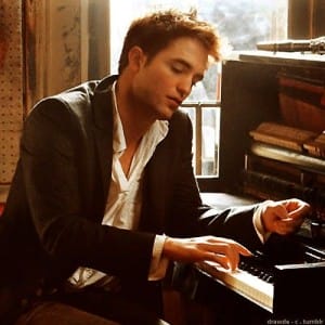 Young man playing the piano, relaxed wearing a black suit.