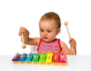 Baby girl, wearing white and black striped T-shirt, playing colorful xylophone. 